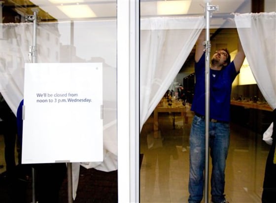An Apple store employee hangs white curtains in the front window of a closed store in Washington to obstruct the view during a memorial service for company co-founder Steve Jobs.